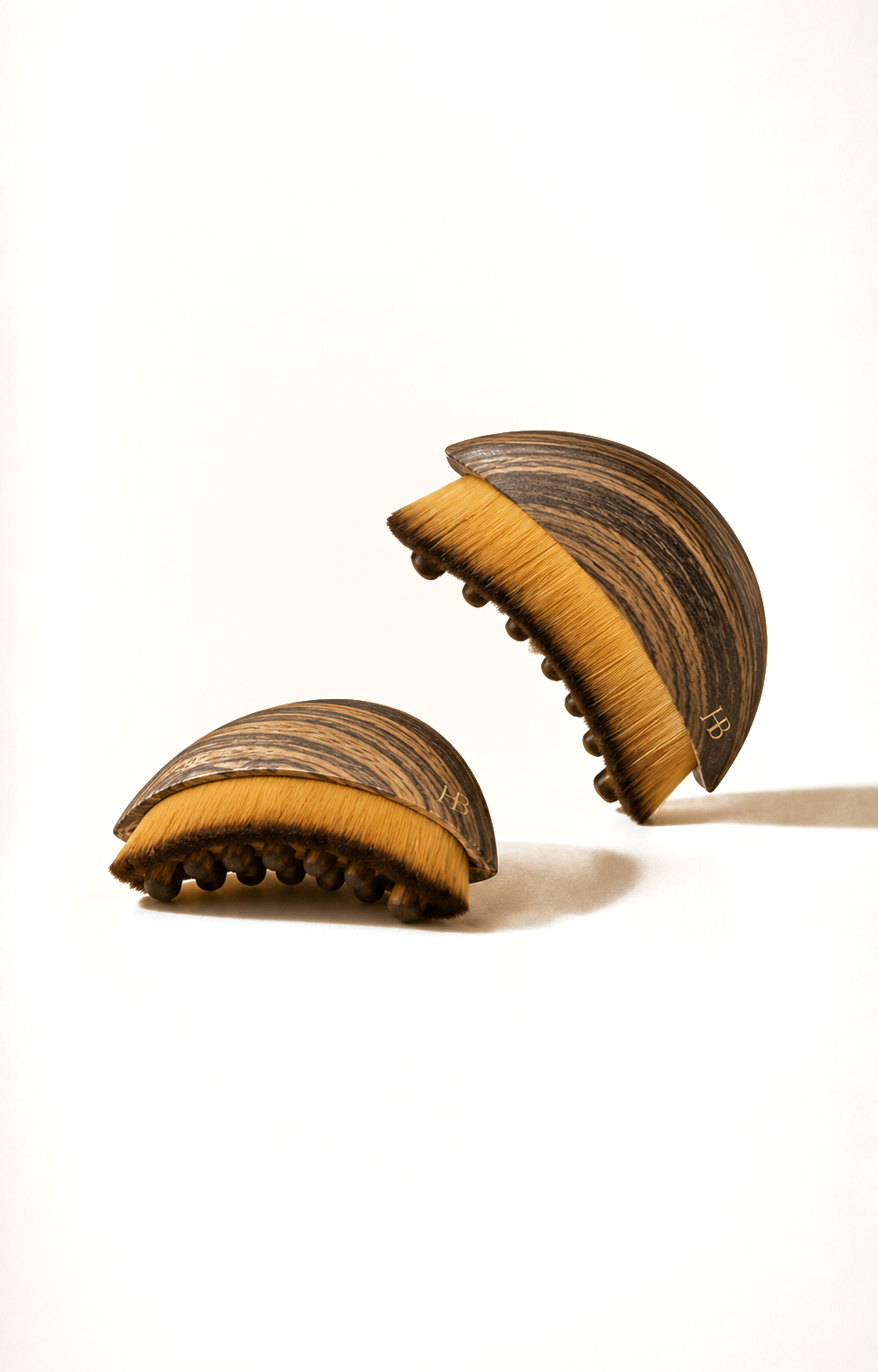 Deux brosses lymphatiques sur fond crème, coque en bois veiné, poils dorés et picots arrondis